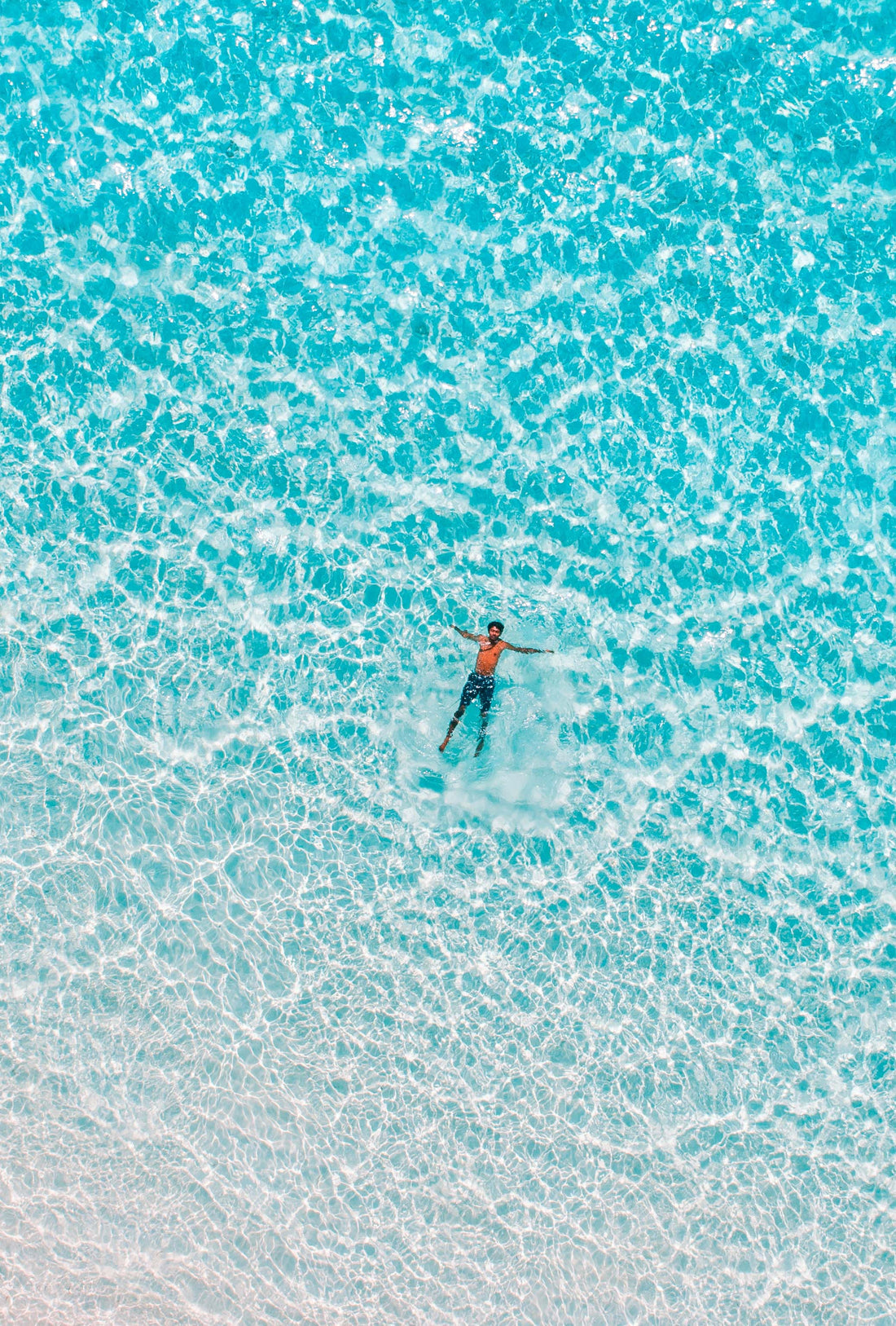 man floating alone in clear ocean water